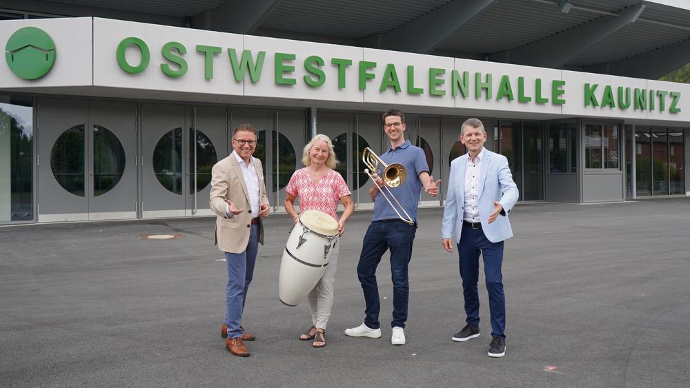 Bürgermeister Robin Rieksneuwöhner, Lilly Menke, Sebastian Stuckmann sowie Bandleader Hans-Josef Piepenbrock (v. l.) vor der Ostwestfalenhalle