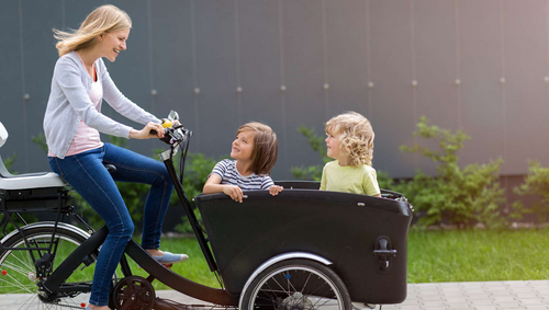 Frau mit zwei Kindern und Lastenrad