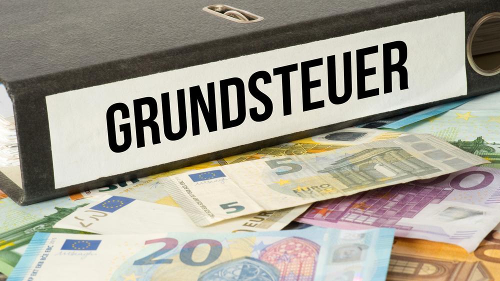 Aktenordner "Grundsteuer" und Geldscheine